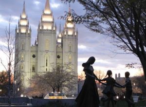 A statue of a mother with her children in front of the Salt Lake City LDS Temple.