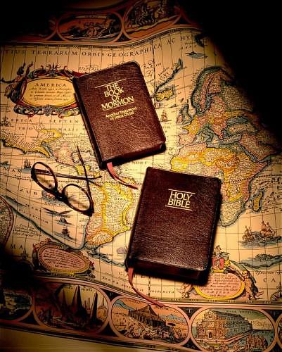 A photo of a copy of The Book of Mormon and the Holy Bible laying on a map.