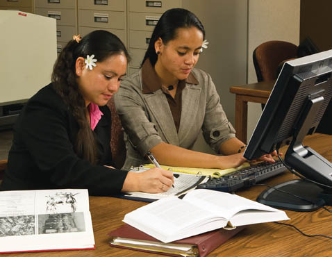 A photo of two Mormon women doing family history together on a computer.