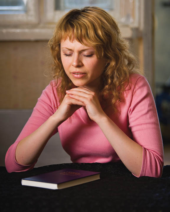 A Mormon woman praying before she studies the scriptures.