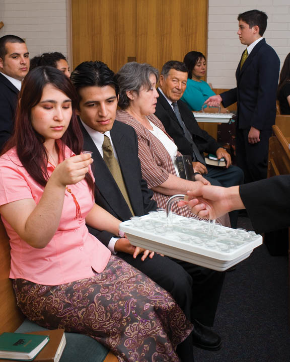 A photo of a woman taking the sacrament during a Mormon sacrament meeting.