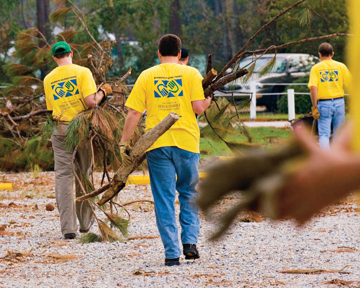 A photo of a few Mormon men helping clear branches as part of a Helping Hands service project. 