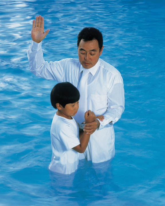 A photo of a Mormon man baptizing a young boy.