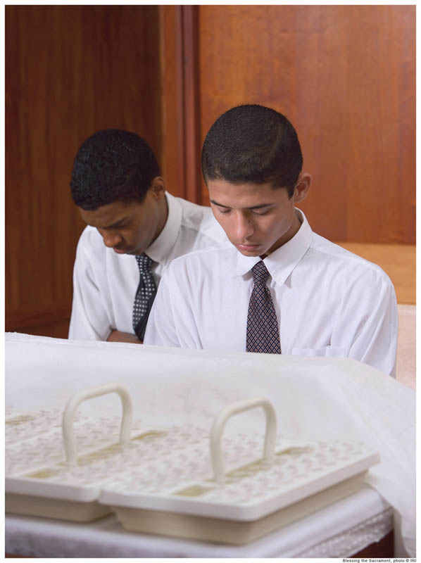 A photo of two young men blessing the sacrament.