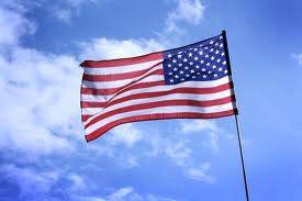 A photo of the American flag blowing in the wind against a partly cloudy sky.