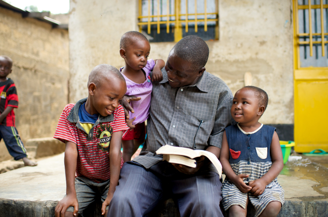 Father studying scriptures with his children