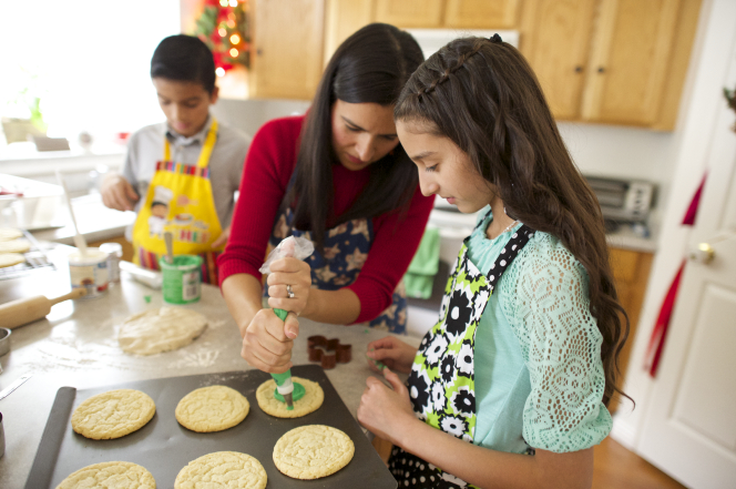 A family decorates cookie together at Christmastime.
