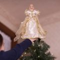 A girl puts an angel on the Christmas tree. We can add our light to the world by serving others this season.