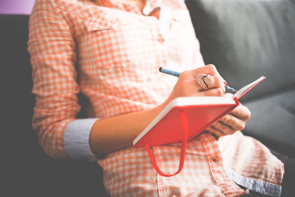 A woman makes a list of her new year's resolutions in a planner.