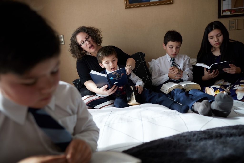 A family studies the scriptures at home.