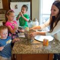 A mom is baking with her children in the kitchen.