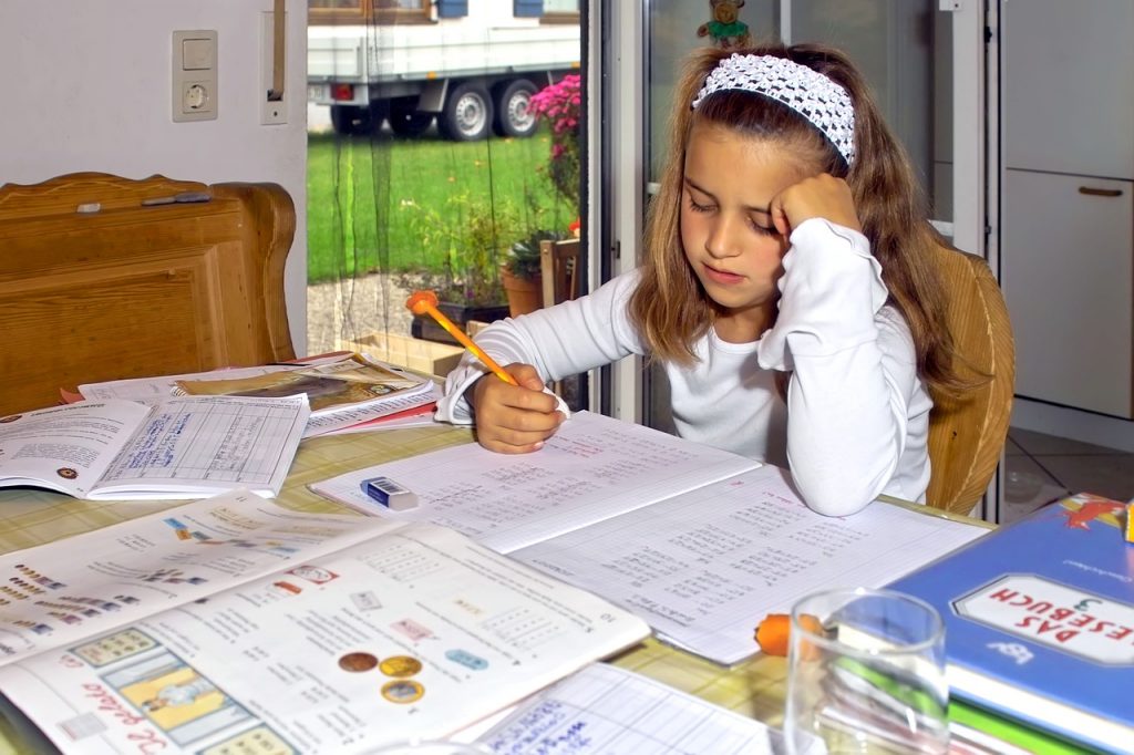 A girl doing schoolwork at the kitchen table.