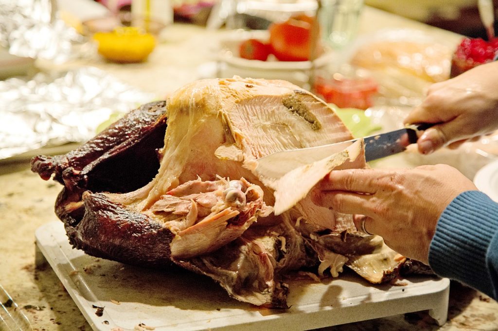 A person cuts a piece off a turkey at Thanksgiving.